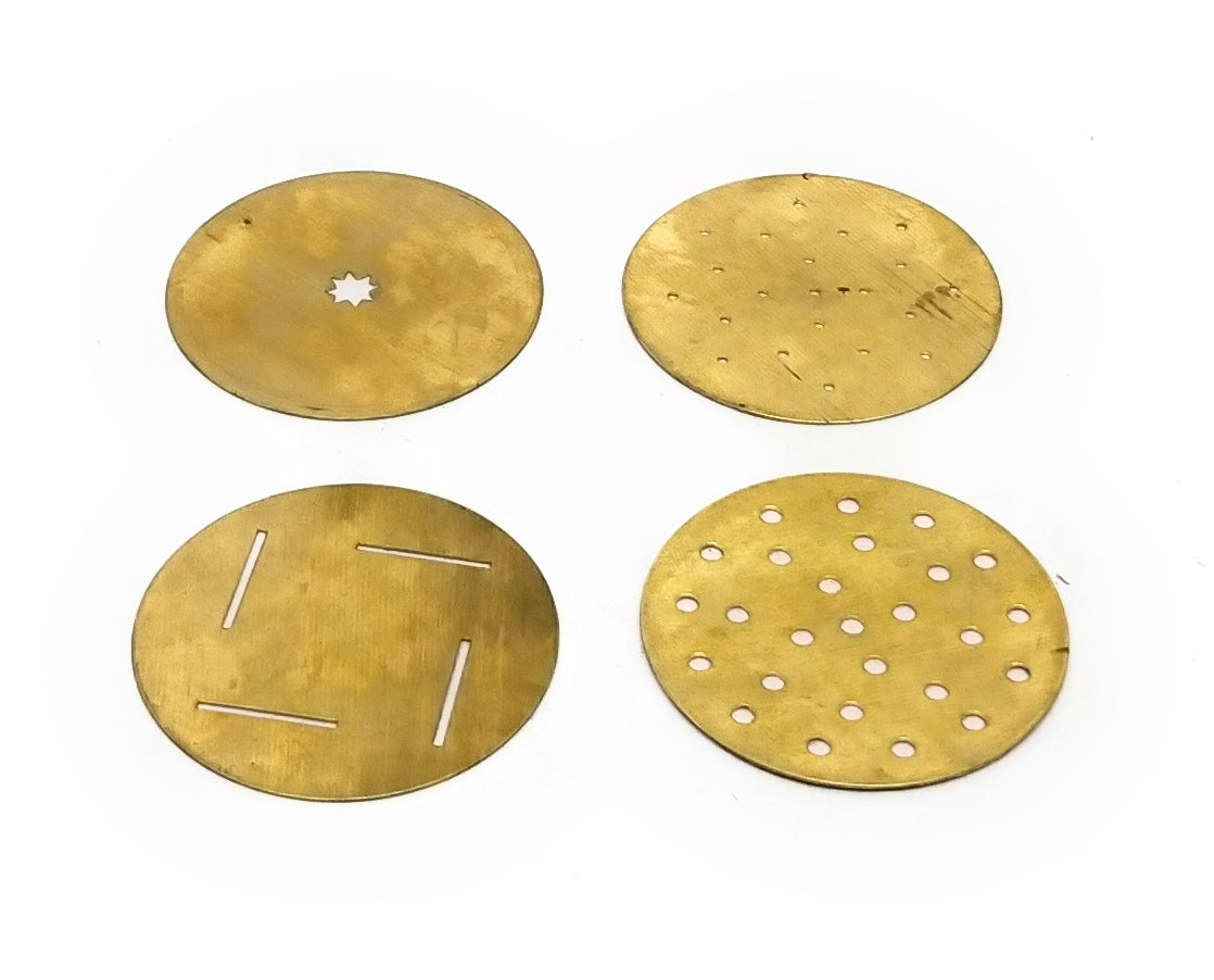 Four round brass-colored metal discs with different cutouts and holes, arranged in a 2x2 grid on a plain white background.