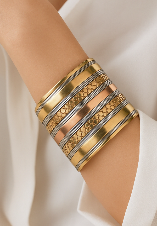 Gold and silver bangles on a person's wrist against a white fabric background
