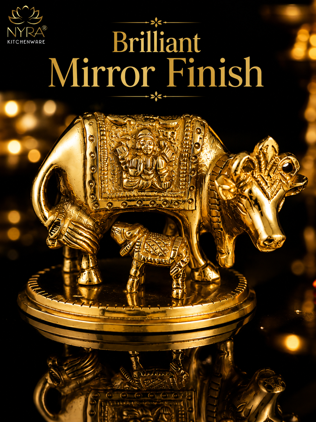 A decorative brass cow and calf figurine with ornate embossed detailing, displayed on a reflective black surface with golden bokeh lights in the background. Text at the top reads 'Brilliant Mirror Finish' with the NYRA KITCHENWARE logo in the upper left.