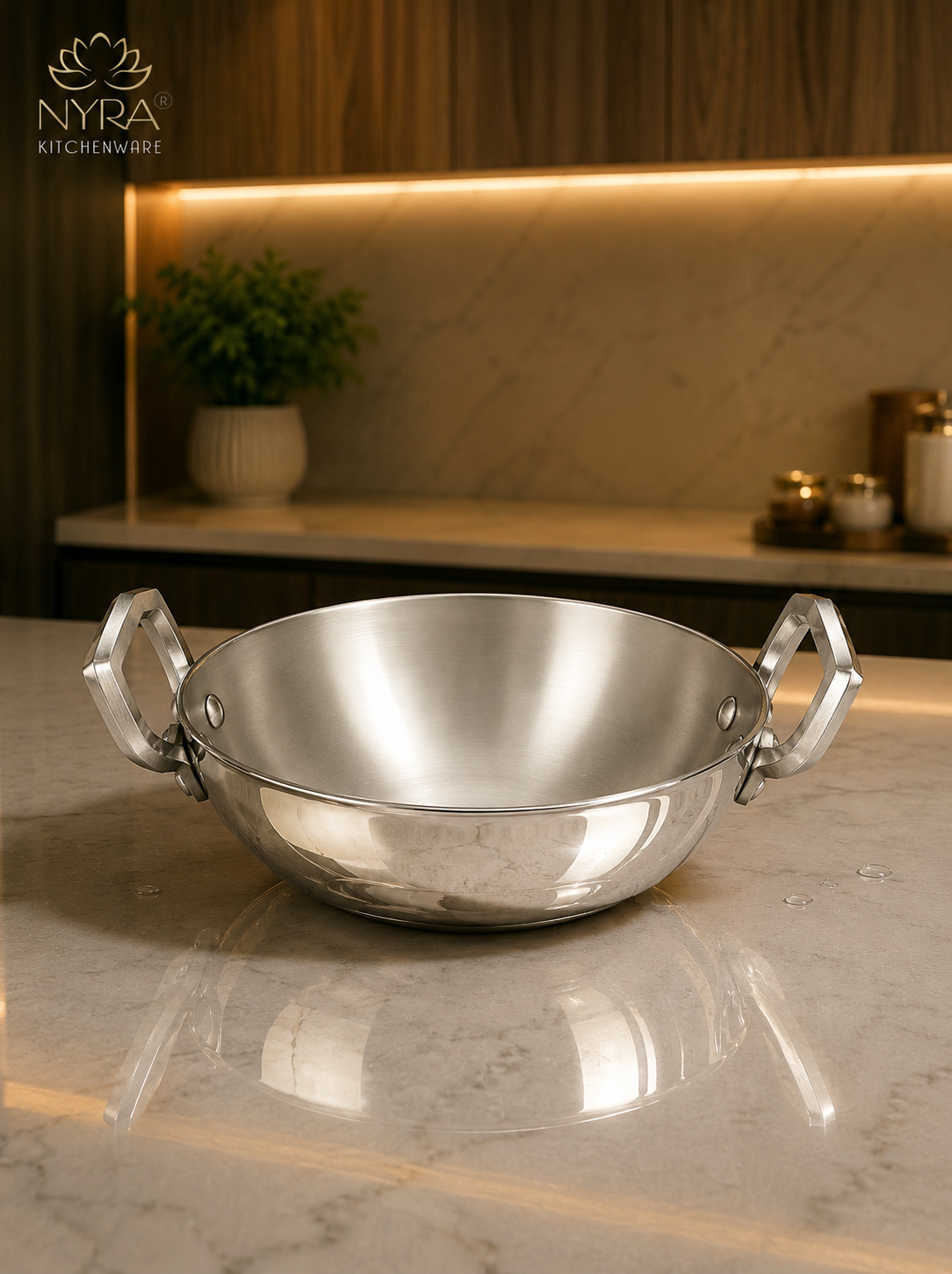 Silver wok with handles on a marble surface, branded 'Nyra Kitchenware'.