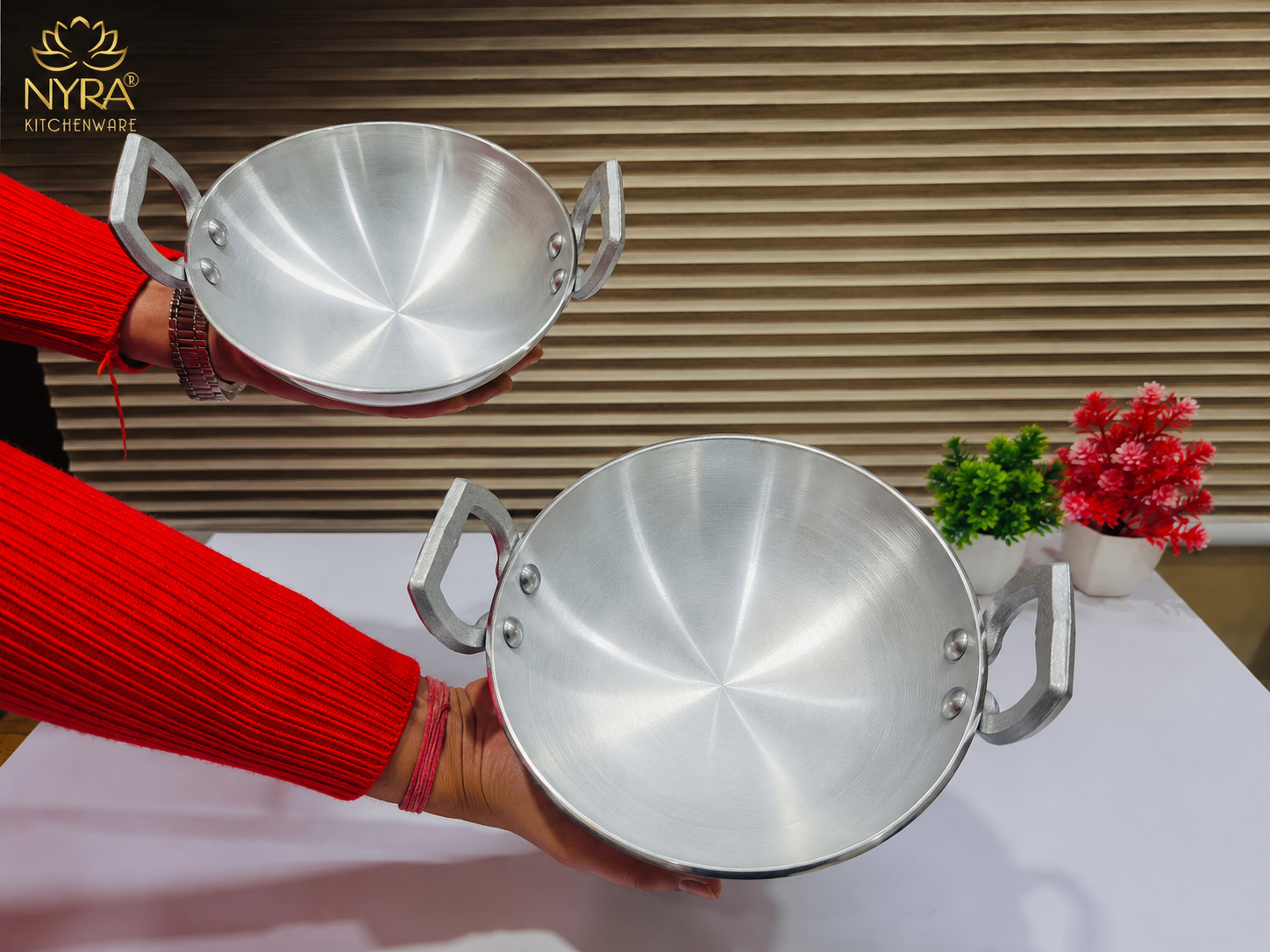 Person holding two silver cookware items with Nyra logo in the corner.