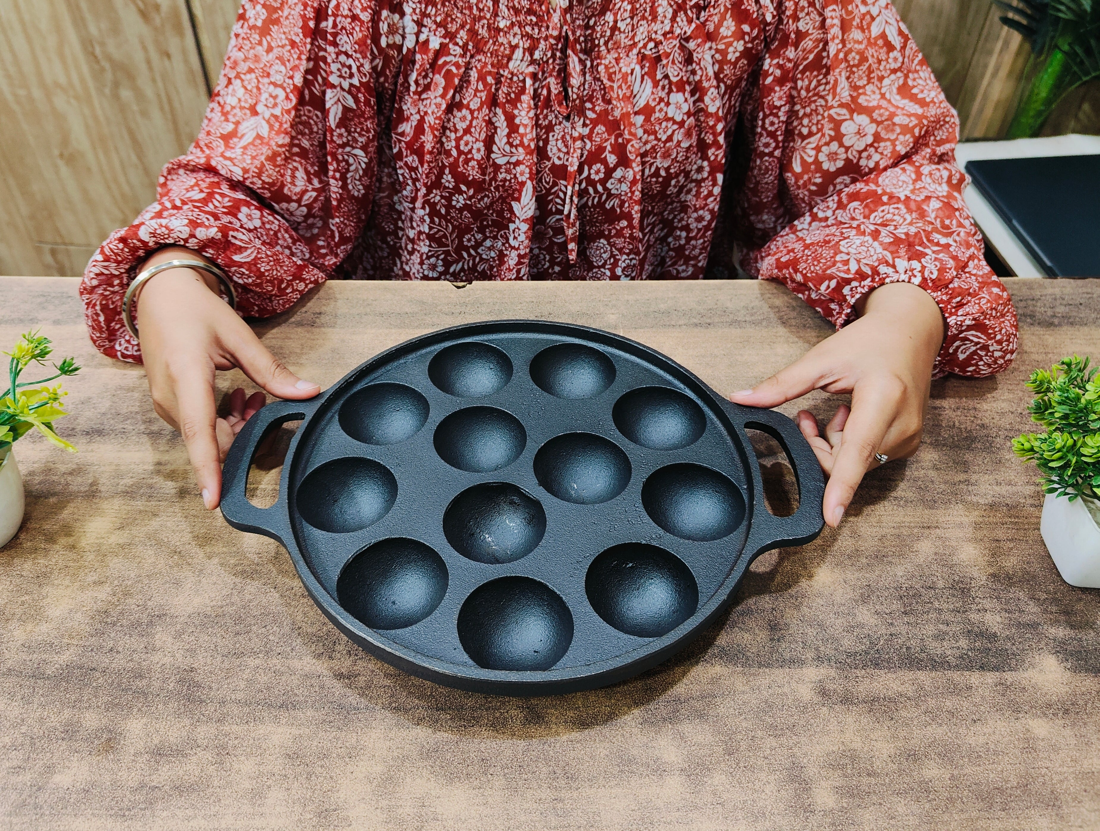 showing in hand Cast Iron Appam Pan