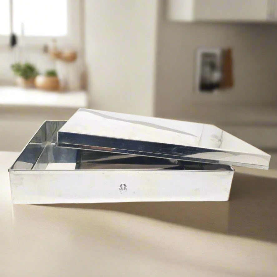 A stainless steel storage container with a lid resting on top, placed on a kitchen countertop.